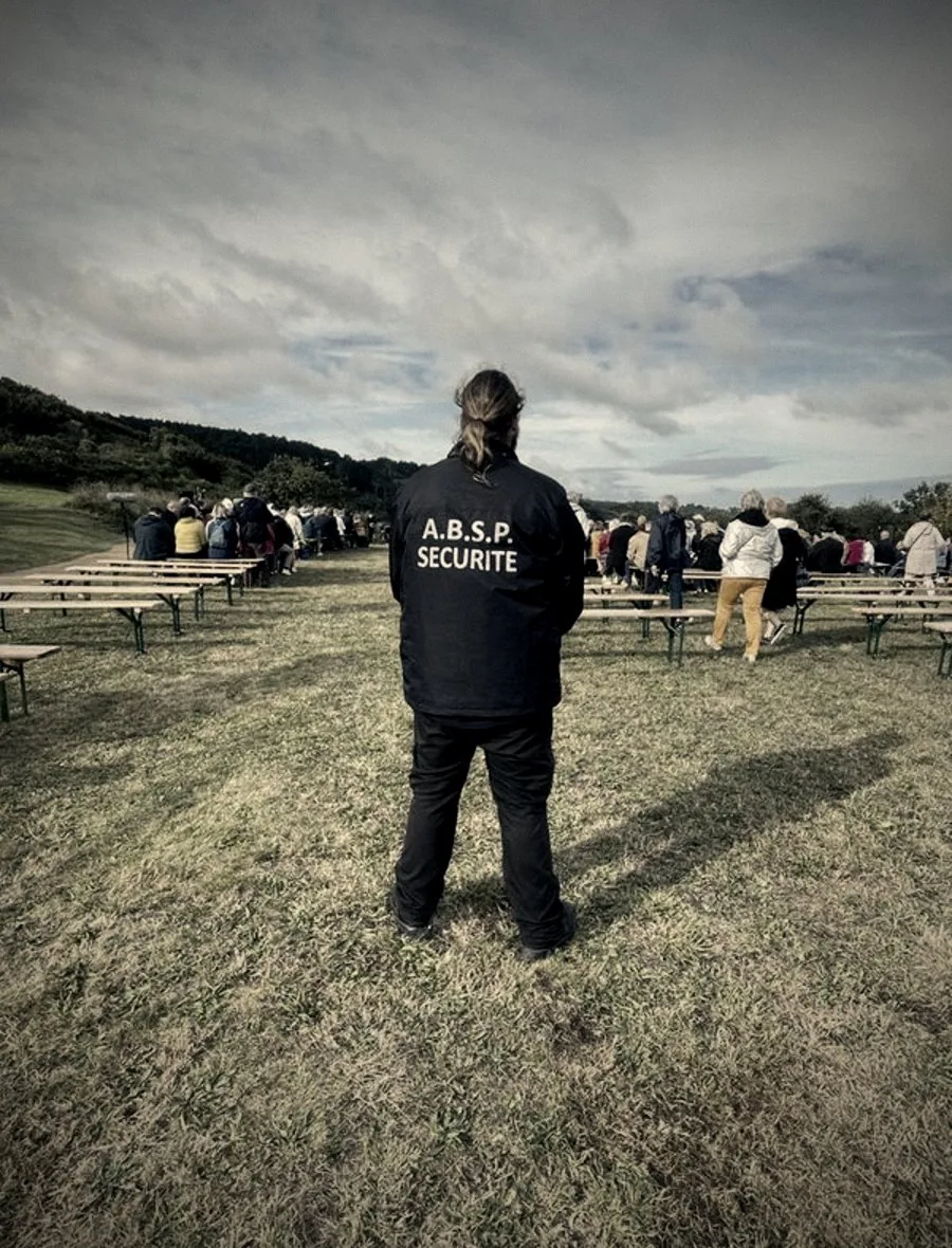 Agent A.B.S.P. en veste sérigraphiée encadrant un rassemblement de plein air